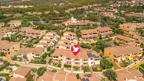 A residential area with multiple two-story houses, some with solar panels, surrounded by greenery and hills in the background. - Cosy apartment for 4 guests with A/C, TV and patio (Villaputzu)