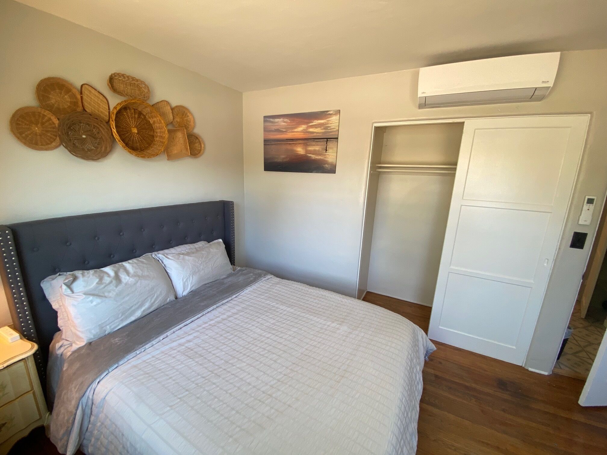A bedroom with a bed, a wardrobe, and a wall-mounted air conditioner.