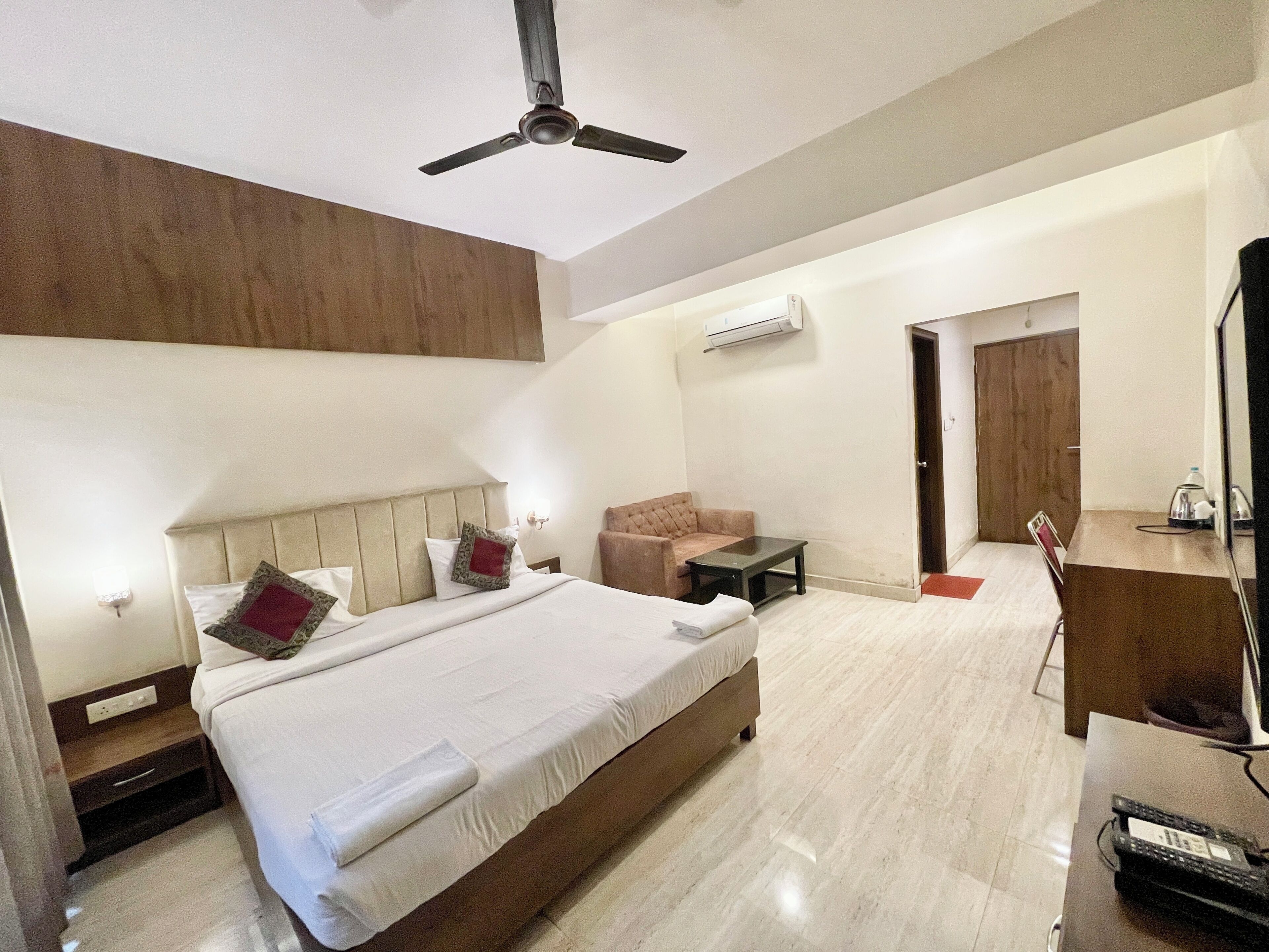 Una habitación de hotel con una cama, un escritorio, una silla, un ventilador de techo y un aire acondicionado.