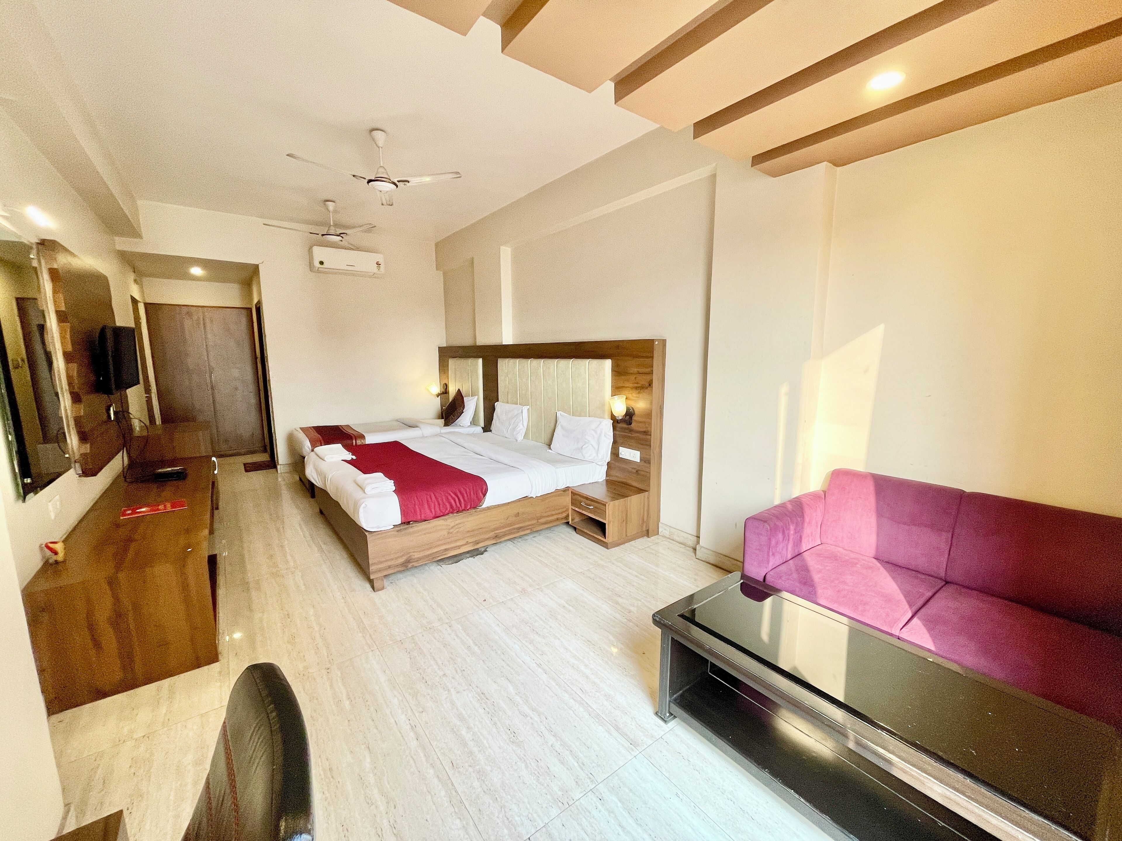 Een moderne hotelkamer met een groot bed, een bureau, een bank en een plafondventilator.