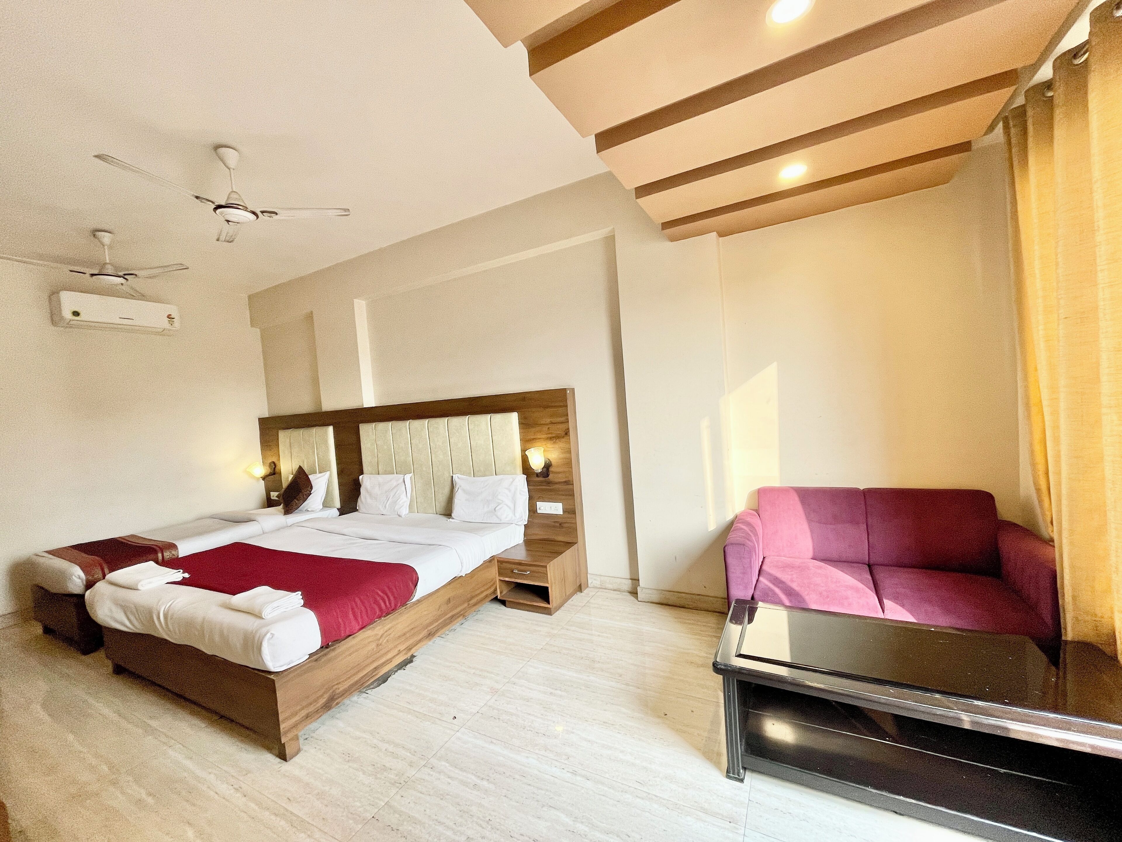 A hotel room with a bed, bedside tables, a desk, a chair, and a ceiling fan.