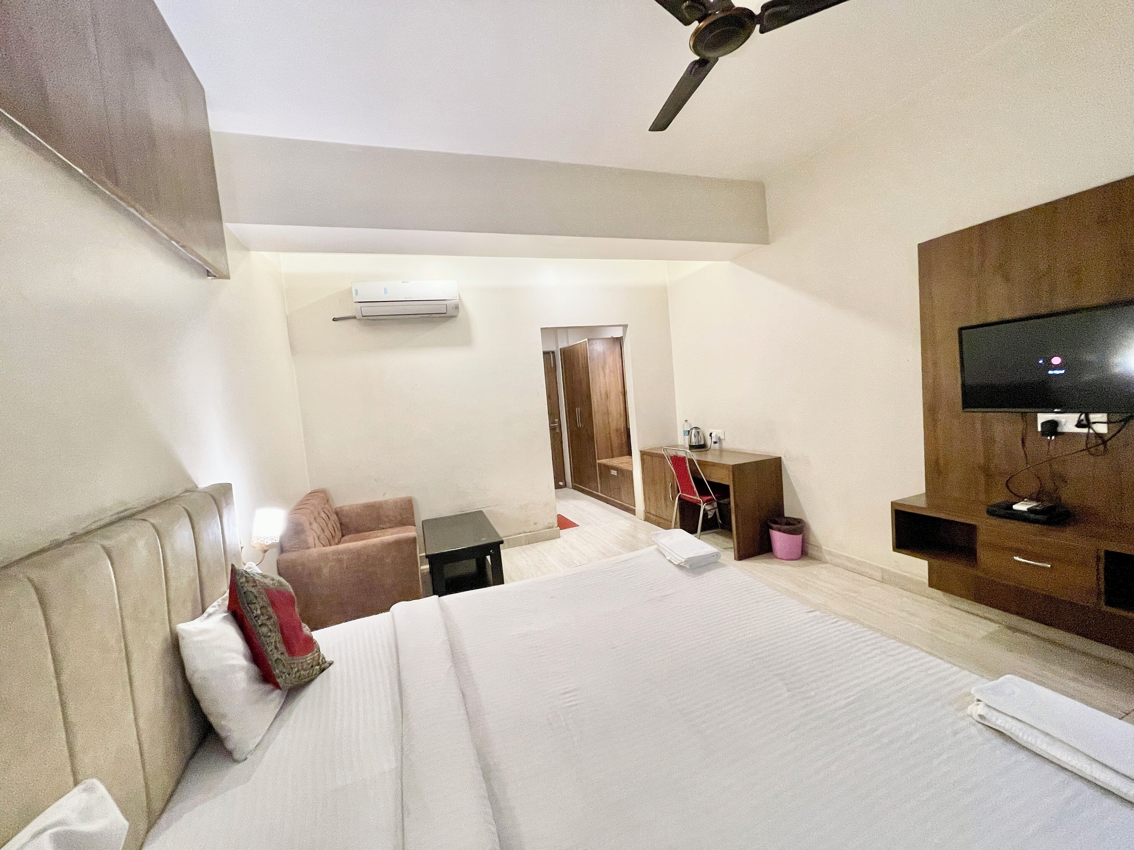 A hotel room with a bed, a desk, a chair, a TV, and a wardrobe.