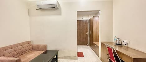 Uma sala de estar moderna com sofá, mesa de centro, escrivaninha com cadeira e ar condicionado.