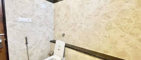 A bathroom with a toilet, a shower, and marble walls.
