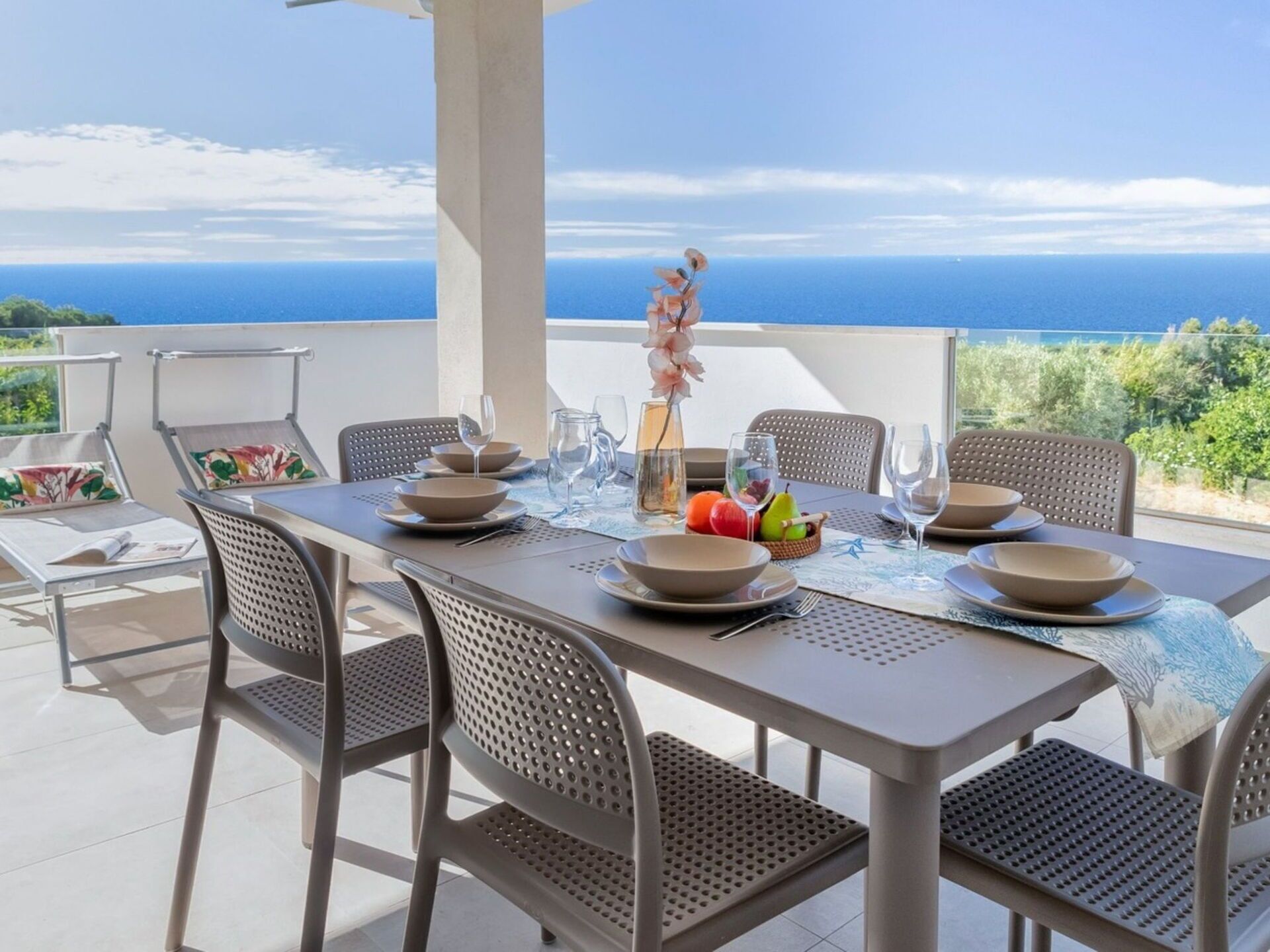 A dining table set for six with a view of the sea.