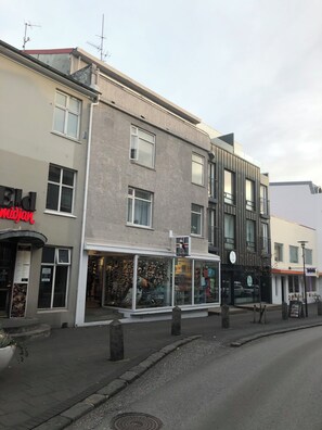 A street view with a building featuring a shop with a red sign, a glass storefront, and a sign indicating a 'No Smoking' area. - Day Dream Downtown Apartments (Reykjavik)