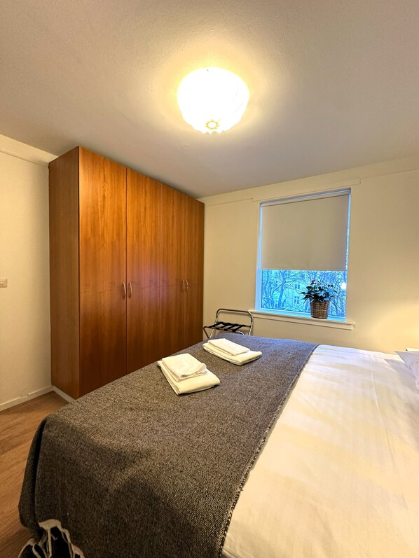 A bedroom with a bed, a wardrobe, a window with a view, and a hanging chair. - Day Dream Downtown Apartments (Reykjavik)