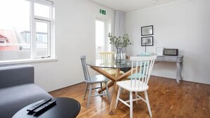 Een moderne kamer met een eettafel, twee stoelen, een bank en een televisie.