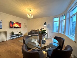 A modern living room with a fireplace, a round glass table, and comfortable seating. - Day Dream Downtown Apartments (Reykjavik)