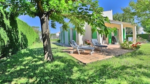 A house with a patio, two lounge chairs, and a tree in the foreground. - Beautiful private villa for 9 people with WIFI, TV and terrace (Saint-denis-d'oléron)