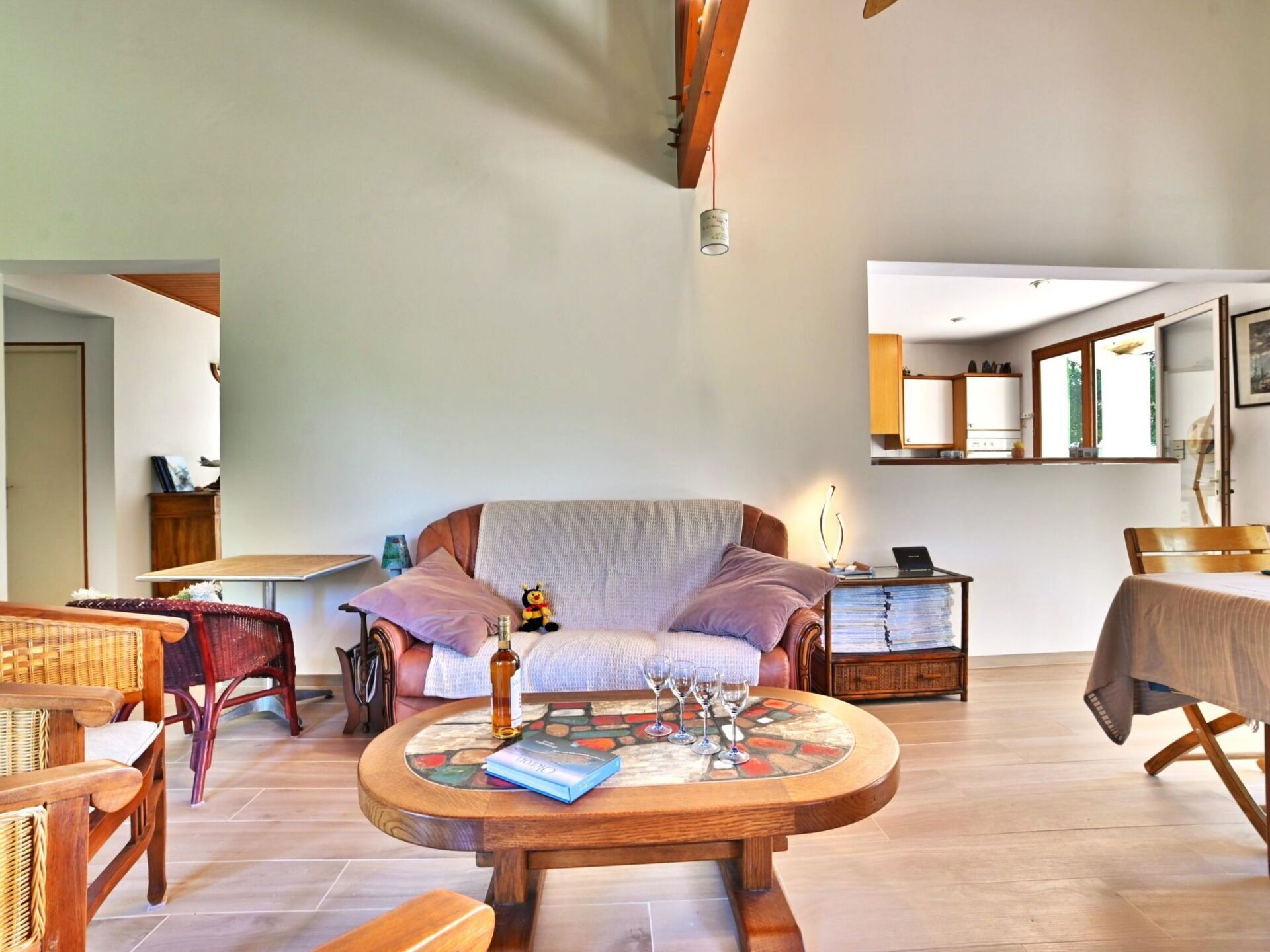 Een gezellige woonkamer met een ronde houten salontafel, een bank en een rieten fauteuil.