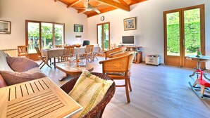 A spacious living area with a high wooden ceiling, a dining table set for four, and a television on a stand. - Beautiful private villa for 9 people with WIFI, TV and terrace (Saint-denis-d'oléron)