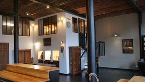 A spacious interior with a wooden reception desk, a staircase, and a black-tiled floor. - Luxury loft in Lille/Tourcoing with sauna, spa, 4 guests, with parking (Tourcoing)