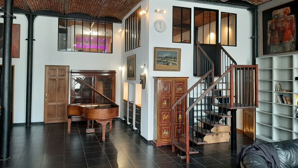 A spacious loft with a grand piano, a staircase, and a bookshelf. - Luxury loft in Lille/Tourcoing with sauna, spa, 4 guests, with parking (Tourcoing)