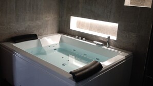 A modern bathroom with a freestanding bathtub, a glass-enclosed shower area, and a wall-mounted light fixture. - Luxury loft in Lille/Tourcoing with sauna, spa, 4 guests, with parking (Tourcoing)