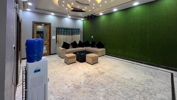 Un salon moderne avec un canapé d’angle, une table basse et un mur texturé de couleur verte.