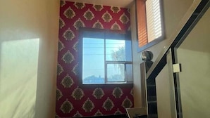 Un couloir avec un mur orné de motifs, une fenêtre et un escalier.