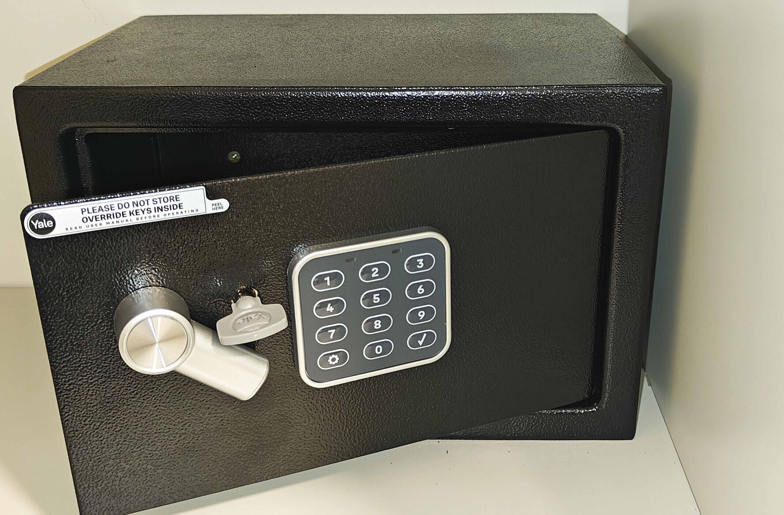 Een zwarte kluis met een numeriek toetsenbord en twee sleutels.