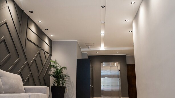 A modern lobby with a sofa, a potted plant, and an elevator. - In the heart of Salta: modern apartment with balcony (Salta)