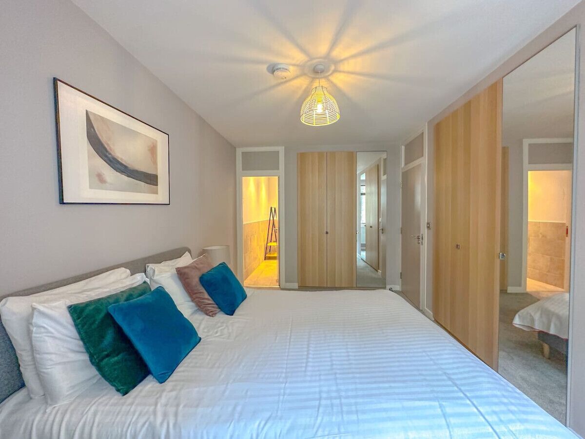 Un dormitorio con una cama grande, una lámpara en el techo y una puerta que da a otra habitación.