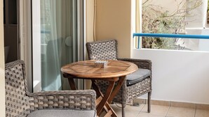 Un balcone con mobili in vimini, un tavolo di legno e vista su piante.
