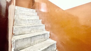 Una scala con una parete marrone e una porta bianca in cima.