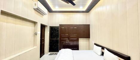 Habitación de hotel con cama, armario y ventilador de techo.