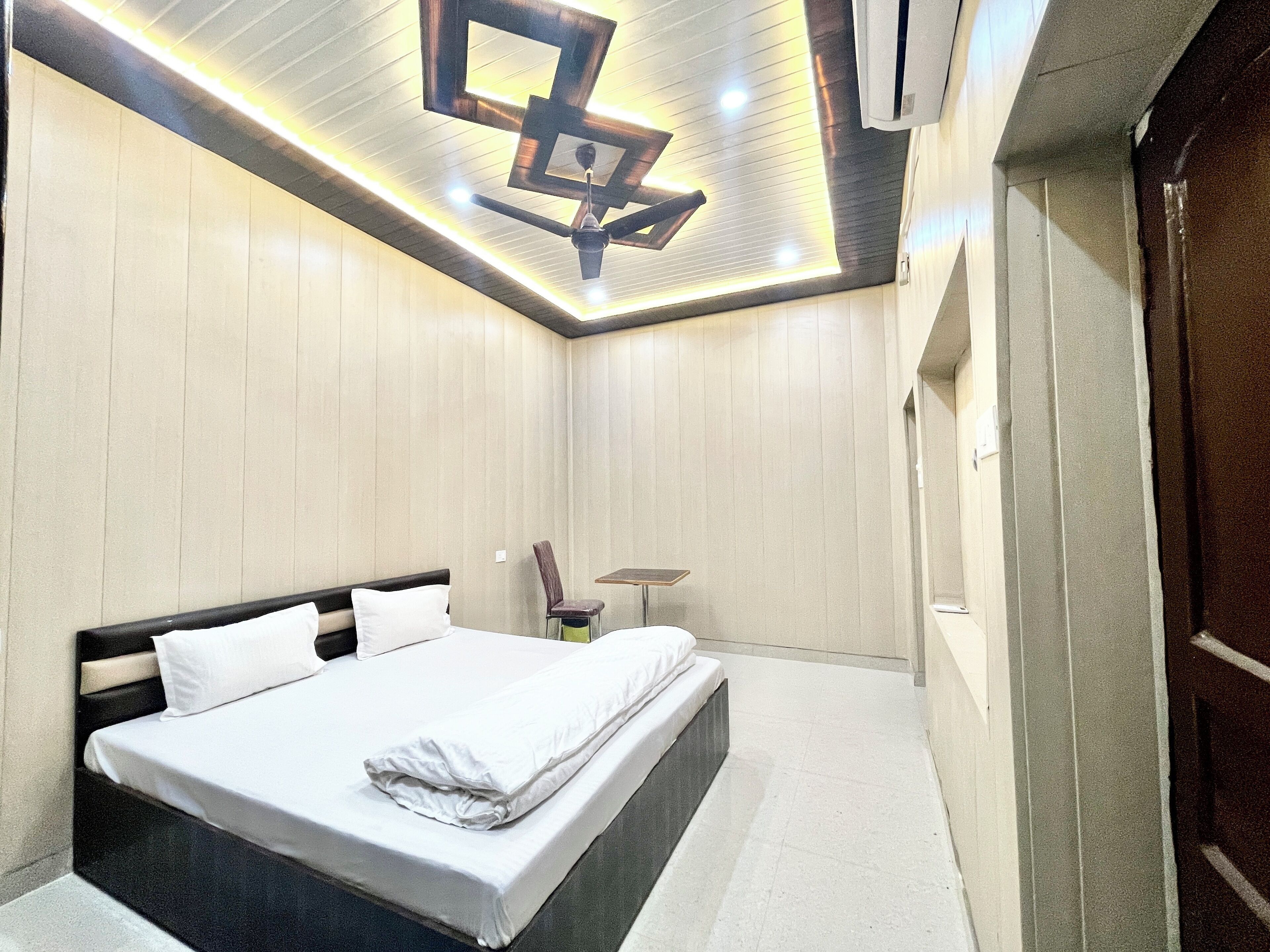 Ein modernes Hotelzimmer mit einem großen Bett, einem Deckenventilator und einem kleinen Tisch.