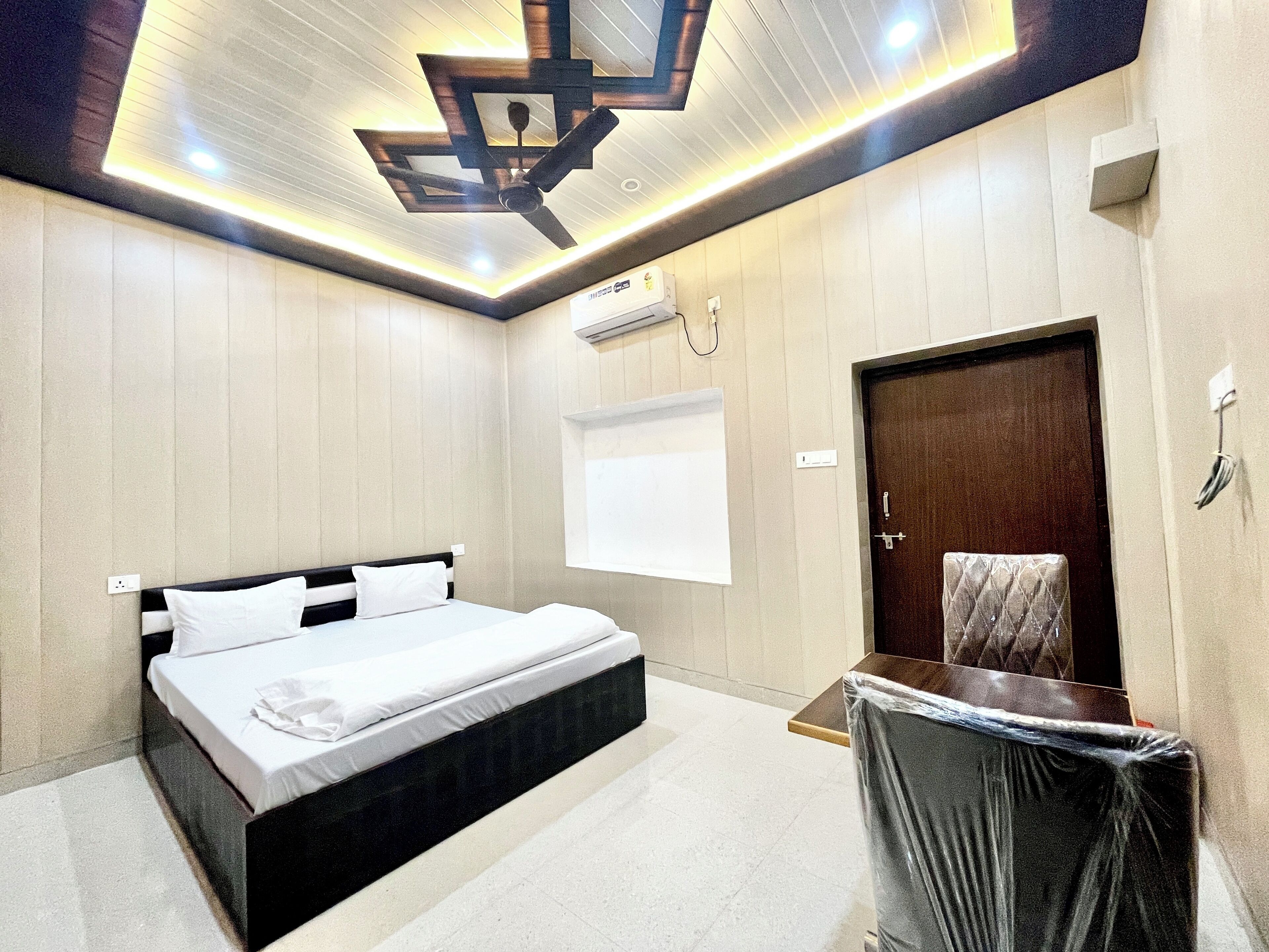 A modern bedroom with a bed, a desk, and a ceiling fan.