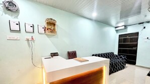 Una zona reception con un bancone bianco, un piccolo altare e un armadio nero.