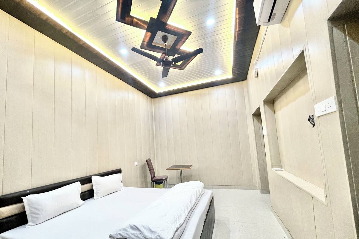 A modern hotel room with a neatly made bed, a ceiling fan, and a small table.