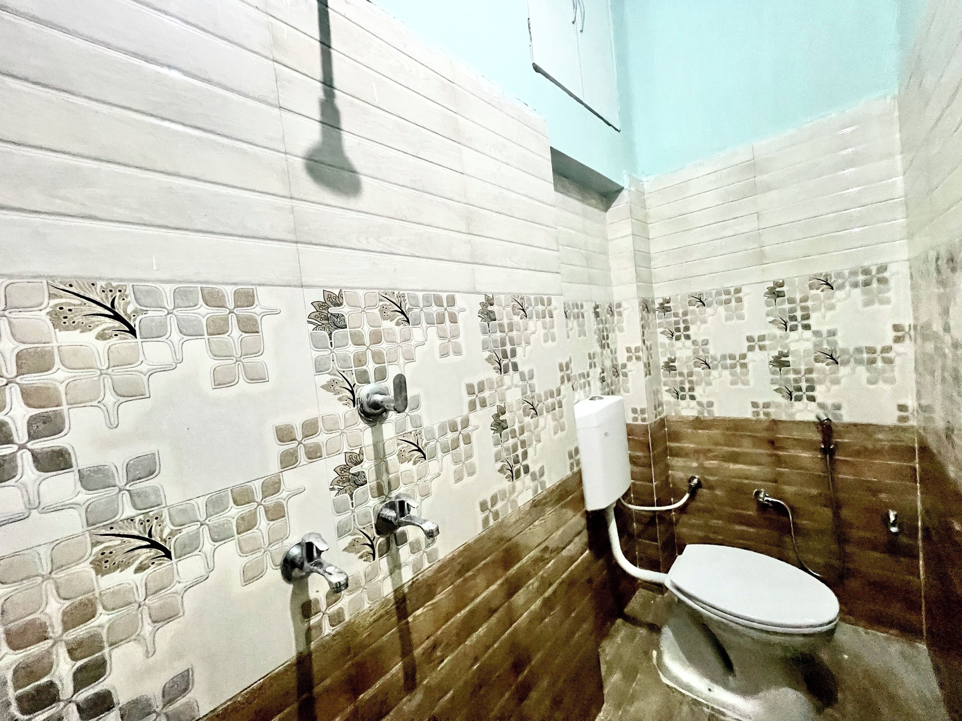 A bathroom with mosaic tiles, a toilet, and a shower.