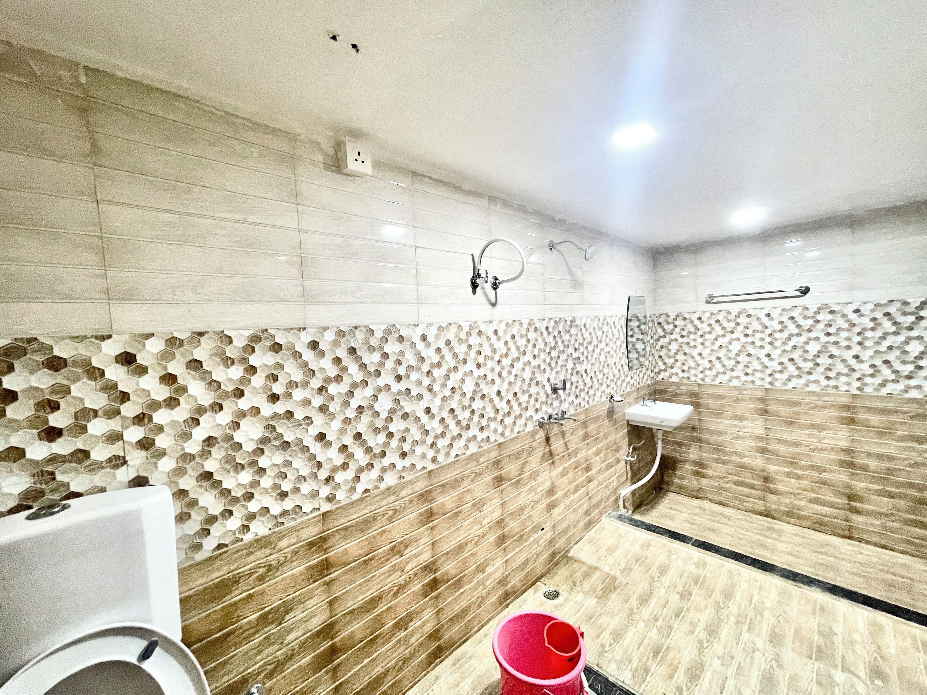 Un baño moderno con pared de azulejos hexagonales, tocador de madera y lavamanos blanco.