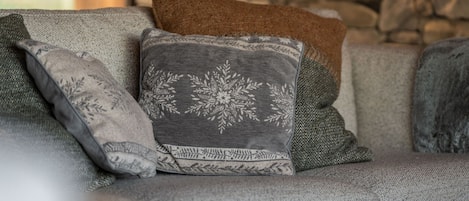 A sofa with multiple cushions, a stone wall in the background, and a hanging light fixture.