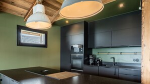 A modern kitchen with dark cabinetry, a central island, and pendant lighting. - Gorgeous 6-room chalet, jacuzzi and sauna, near slopes in La Plagne Montalbert (La Plagne Montalbert)