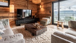 A cozy log cabin interior with a television, seating area, and a balcony with a mountain view. - Gorgeous 6-room chalet, jacuzzi and sauna, near slopes in La Plagne Montalbert (La Plagne Montalbert)