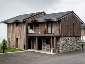 Une maison en bois à deux étages, avec des fondations en pierre, un balcon et une entrée en pierre.