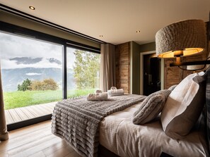 Une chambre avec une grande fenêtre, un lit avec une couverture et une lampe.