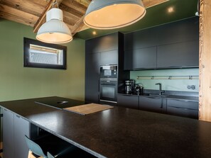 A modern kitchen with dark cabinetry, a central island, and pendant lighting.