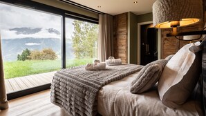 A bedroom with a large window, a bed with a blanket, a lamp, and a view of mountains. - Gorgeous 6-room chalet, jacuzzi and sauna, near slopes in La Plagne Montalbert (La Plagne Montalbert)