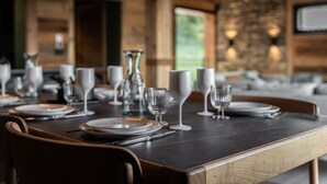 A dining table set with plates, glasses, and cutlery in a wooden interior with a stone wall and a hanging light fixture. - Gorgeous 6-room chalet, jacuzzi and sauna, near slopes in La Plagne Montalbert (La Plagne Montalbert)