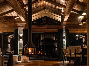 A cozy interior with a fireplace, wooden beams, and comfortable seating.