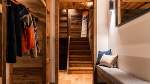 Een houten interieur met een bank, een trap en een snowboard dat tegen de muur staat.