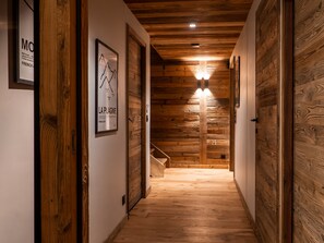 Un pasillo interior de madera con una escalera, paredes de madera y un cartel enmarcado en la pared.