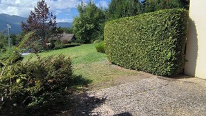 A gravel path leading to a house with a well-maintained hedge and a view of mountains in the background. - Renovated 2-bedroom apartment in Samoëns, pets allowed (Samoëns)