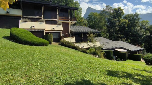 A two-story house with a sloped roof, surrounded by well-maintained lawns and trees. - Renovated 2-bedroom apartment in Samoëns, pets allowed (Samoëns)