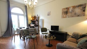 A living room with a sofa, chairs, a coffee table, a TV, and a fireplace. - 52m² Apt, 4 pers, Casino area, WiFi, Parking (Bagnères-de-Luchon)