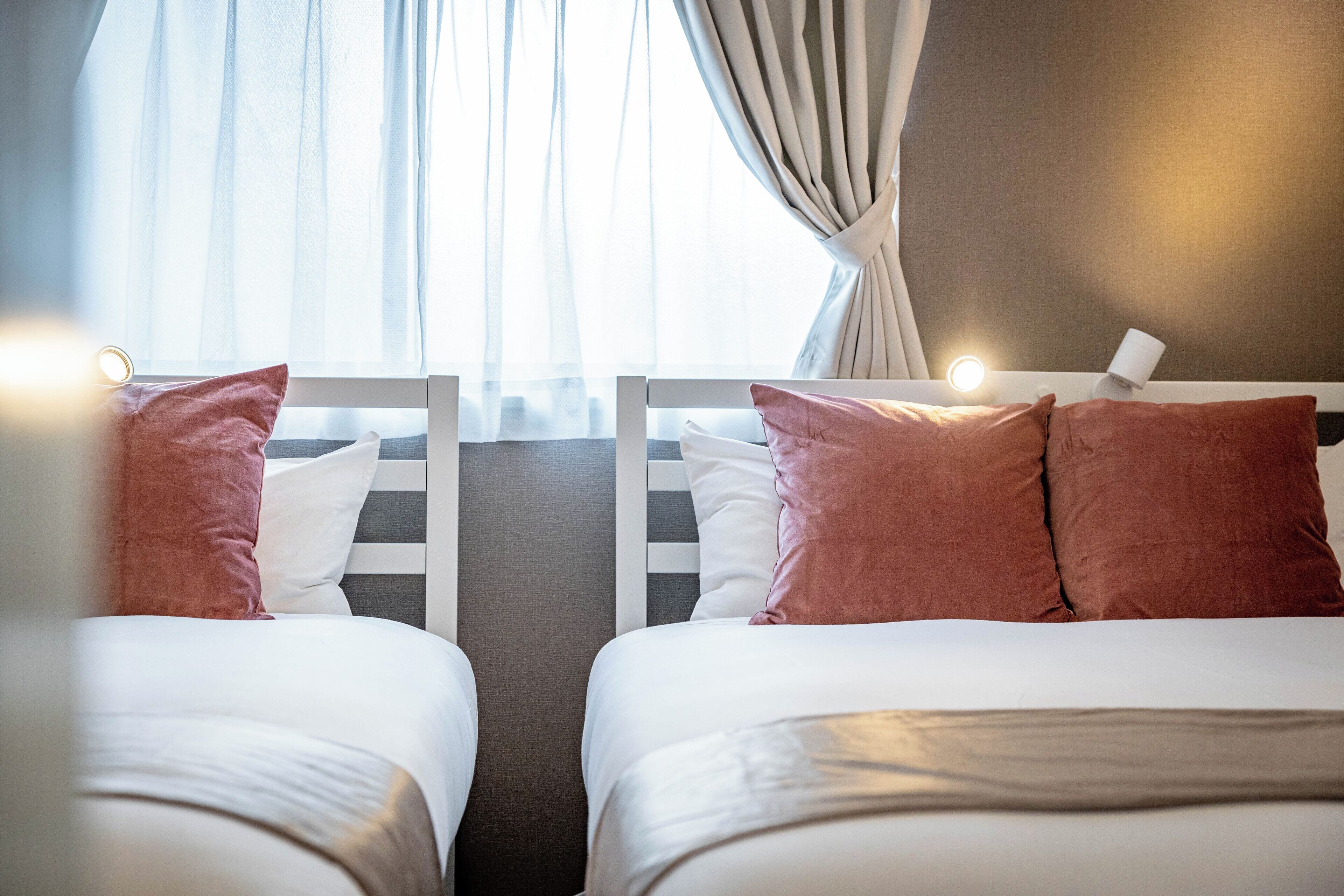 A hotel room with two beds, each with white bedding and pink pillows.