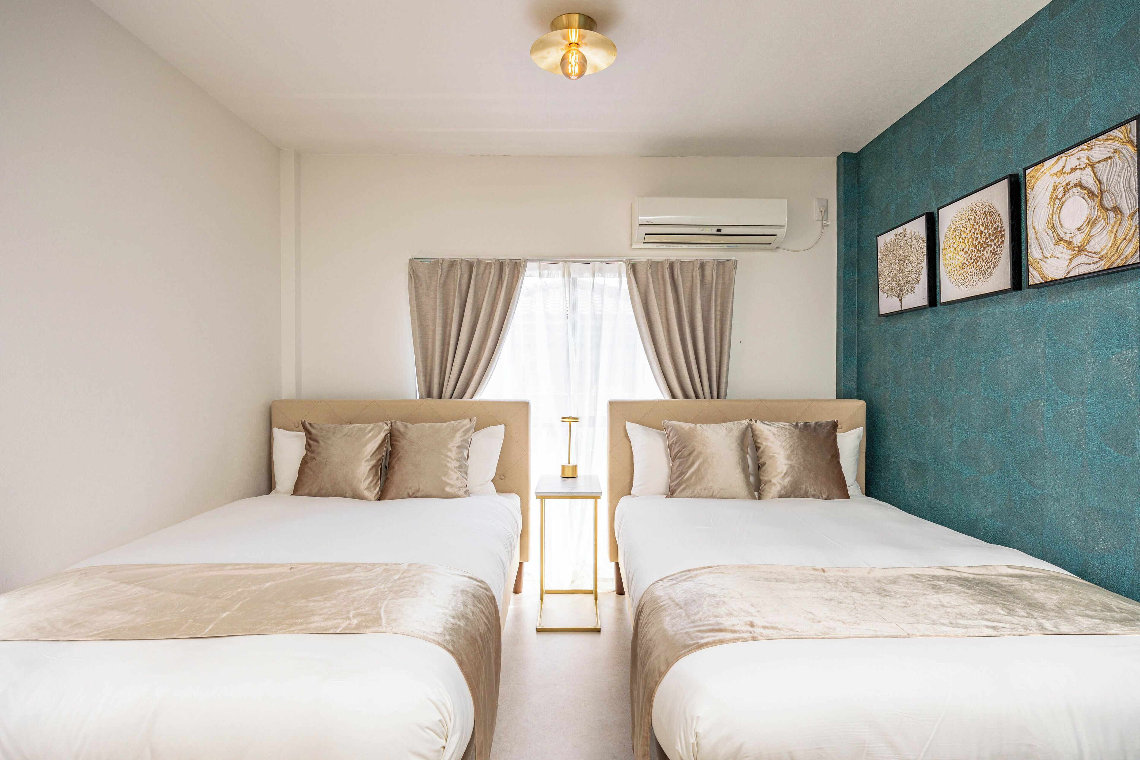 Ein Hotelzimmer mit zwei Betten, einem kleinen Nachttisch, einer Klimaanlage und einem fenster mit Vorhängen.