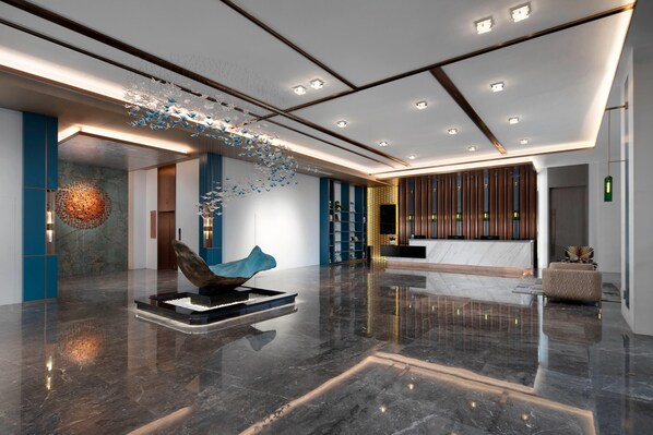 A modern lobby with a reception desk, a sculpture, and a patterned wall.